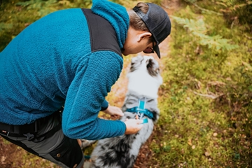 Mand i turkis hoodie sammen med hund